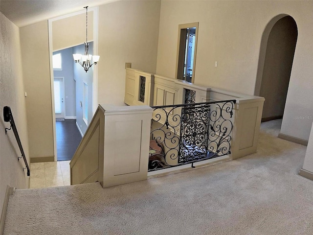 interior space with a chandelier, arched walkways, baseboards, and an upstairs landing