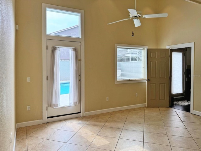 foyer entrance featuring a wealth of natural light, light tile patterned flooring, a towering ceiling, and baseboards