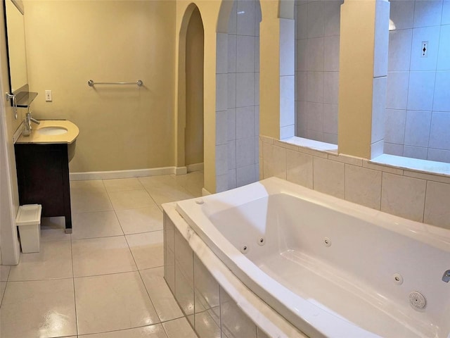 bathroom featuring tile patterned flooring, a tub with jets, baseboards, and vanity