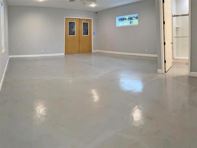 interior space featuring concrete flooring, a ceiling fan, and baseboards