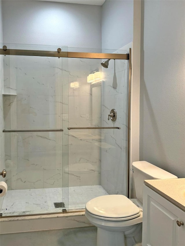 bathroom featuring toilet, a marble finish shower, and vanity