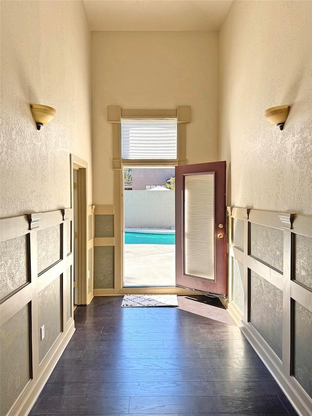 hallway featuring dark wood-style floors and a textured wall