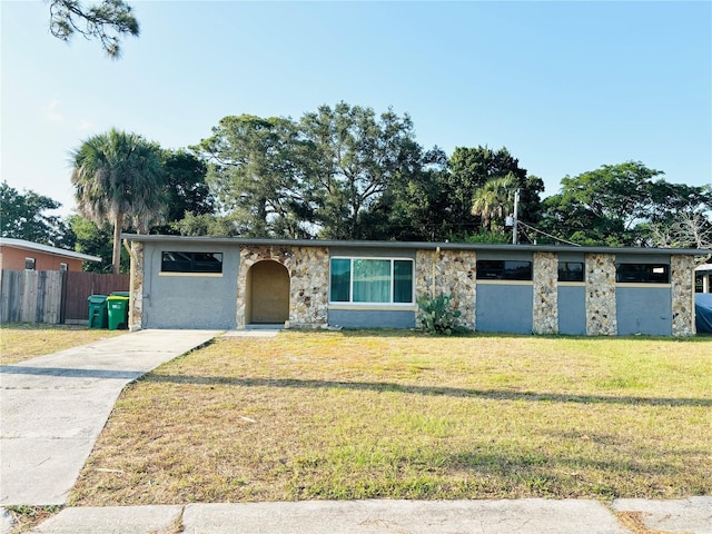 mid-century home with driveway, stone siding, fence, a front yard, and stucco siding