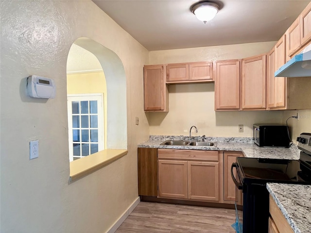 kitchen featuring light brown cabinetry, electric range, under cabinet range hood, and a sink