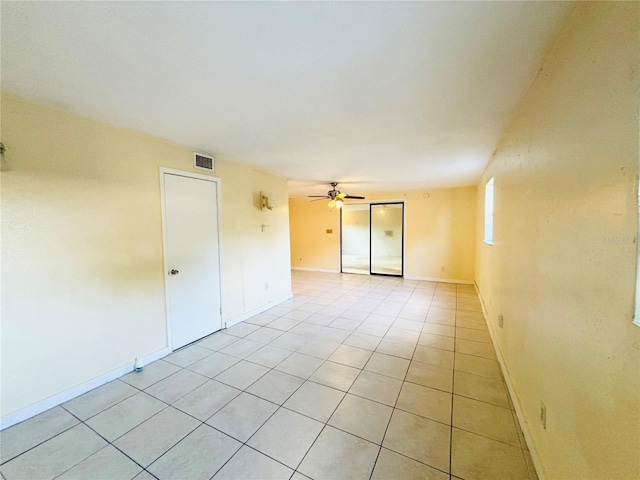 unfurnished room featuring light tile patterned floors, visible vents, baseboards, and a ceiling fan