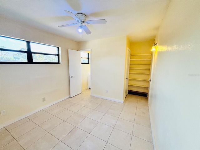 spare room featuring light tile patterned floors, baseboards, and a ceiling fan