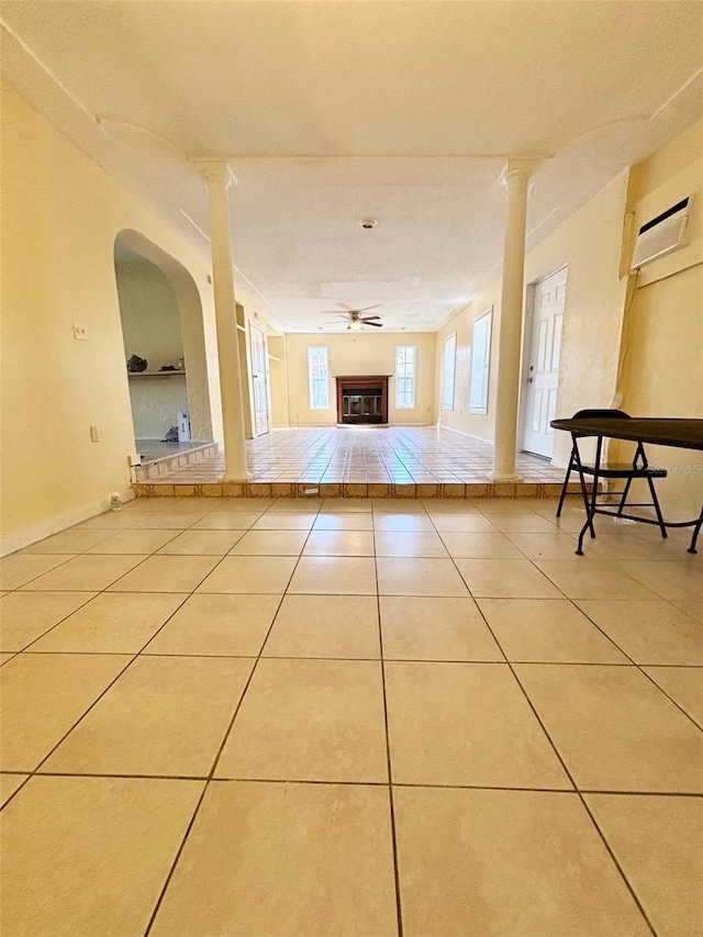 hall featuring tile patterned flooring, decorative columns, baseboards, and a wall mounted air conditioner