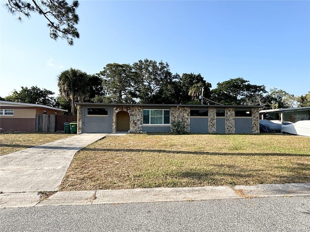 mid-century modern home with stone siding, concrete driveway, a front yard, and fence