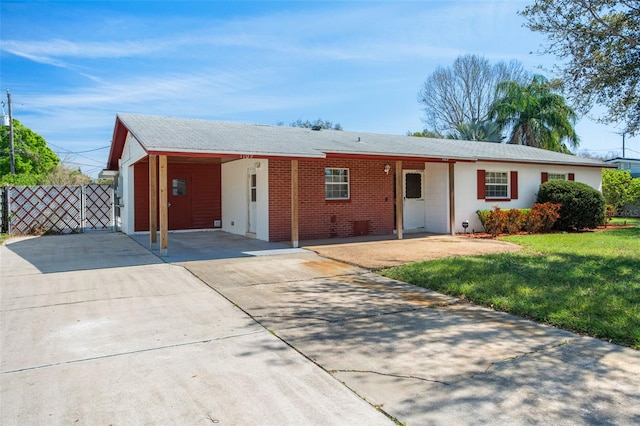 ranch-style home with brick siding, fence, driveway, a carport, and a front lawn