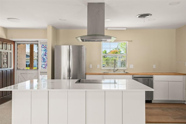 kitchen featuring island exhaust hood, appliances with stainless steel finishes, light countertops, and a sink