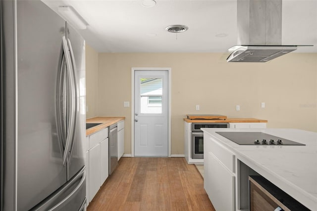 kitchen featuring visible vents, island exhaust hood, stainless steel appliances, light wood-type flooring, and white cabinetry