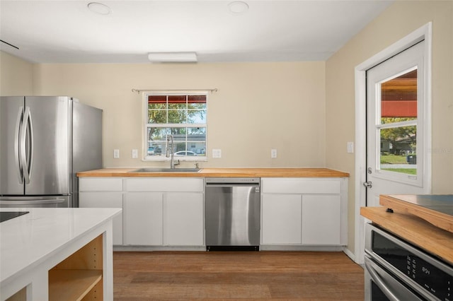 kitchen with plenty of natural light, wood counters, appliances with stainless steel finishes, and a sink