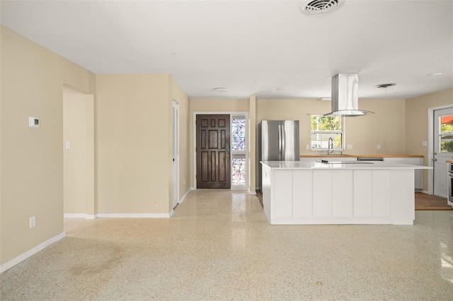 kitchen with visible vents, a kitchen island, appliances with stainless steel finishes, light countertops, and light speckled floor