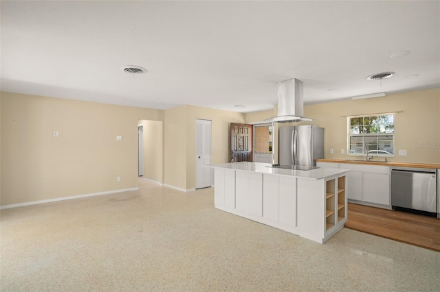 kitchen featuring island range hood, visible vents, appliances with stainless steel finishes, white cabinetry, and light speckled floor