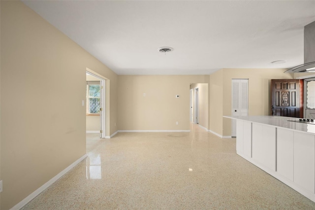 unfurnished living room featuring light speckled floor, visible vents, and baseboards