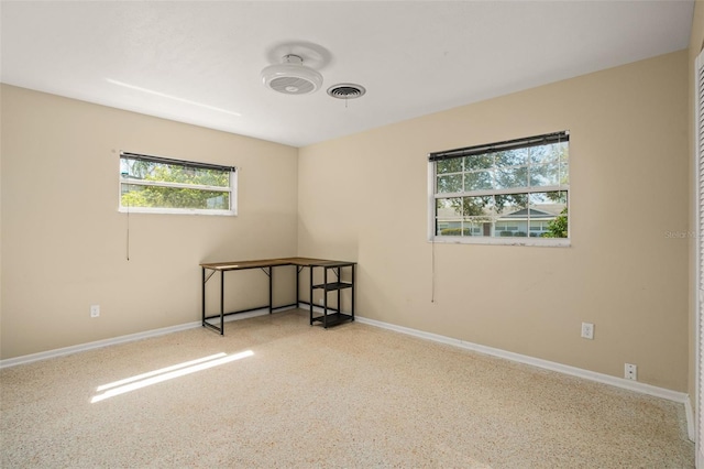 empty room with speckled floor, visible vents, and baseboards