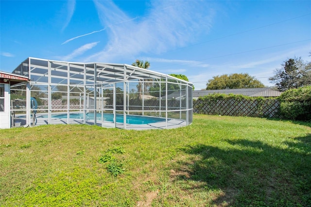 view of swimming pool featuring a yard, glass enclosure, fence private yard, and a fenced in pool