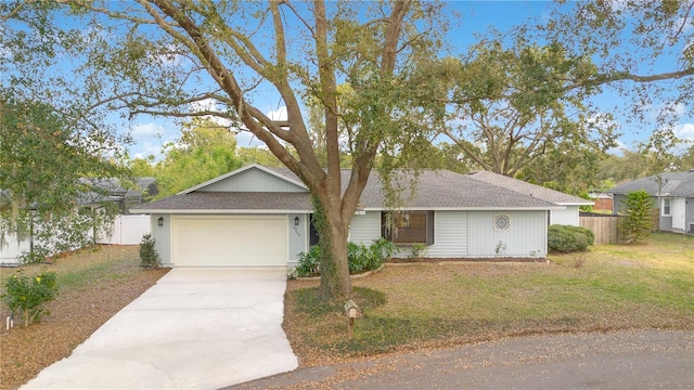 ranch-style home with driveway, a front lawn, an attached garage, and fence