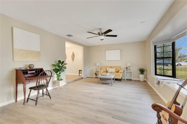 living area with light wood-type flooring, visible vents, and baseboards