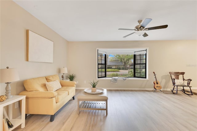 living room featuring ceiling fan, baseboards, and wood finished floors