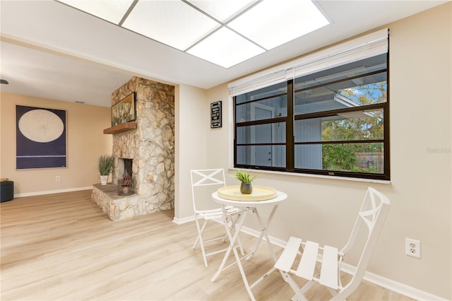 dining area featuring a stone fireplace, wood finished floors, and baseboards