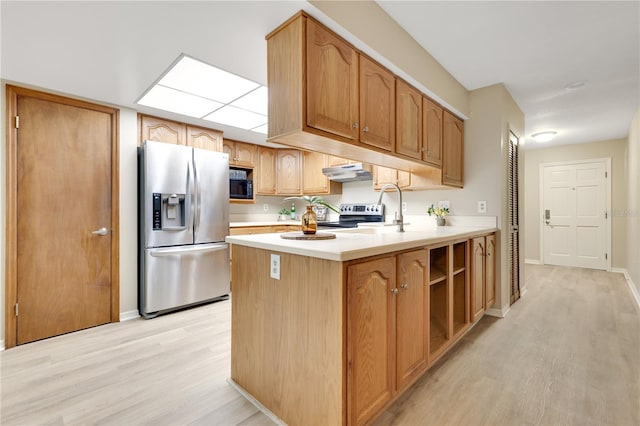 kitchen with light wood-style floors, appliances with stainless steel finishes, light countertops, under cabinet range hood, and a sink