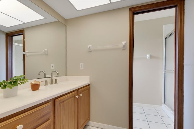 full bathroom featuring a skylight, tile patterned flooring, a shower stall, and vanity