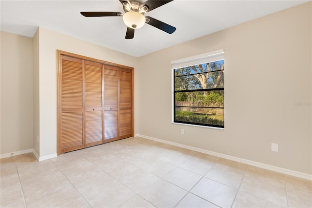 unfurnished bedroom with light tile patterned floors, a ceiling fan, baseboards, and a closet