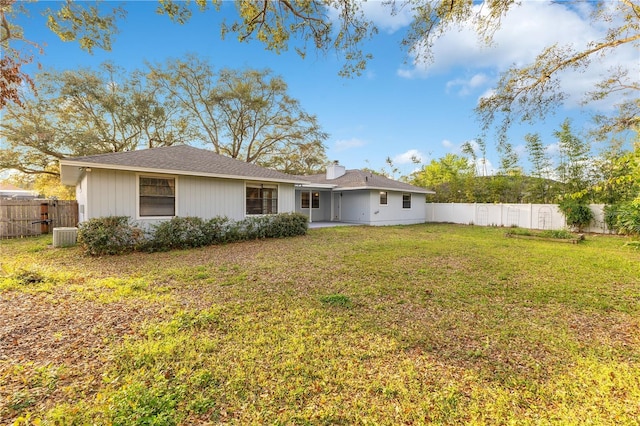 back of property with a fenced backyard, a chimney, and a lawn