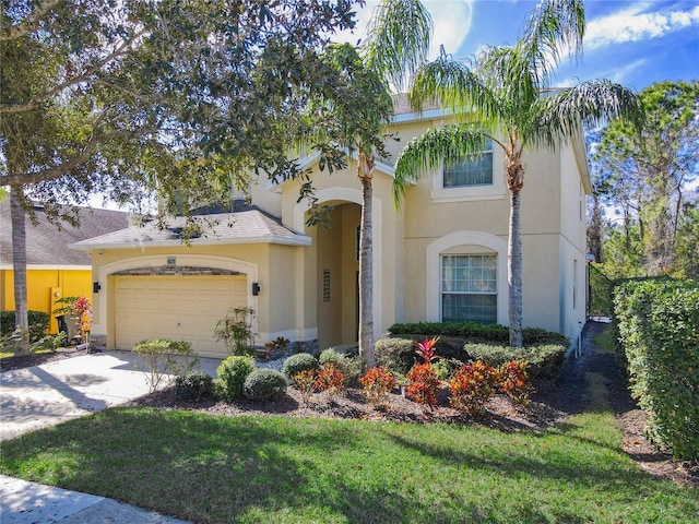 mediterranean / spanish home featuring concrete driveway, roof with shingles, an attached garage, a front lawn, and stucco siding