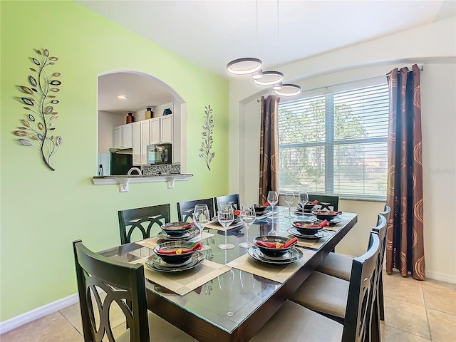 dining area with light tile patterned floors, baseboards, and arched walkways