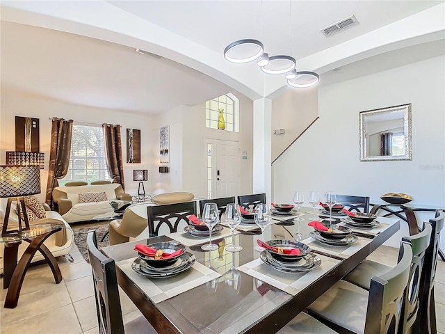 dining area featuring light tile patterned floors, arched walkways, and visible vents