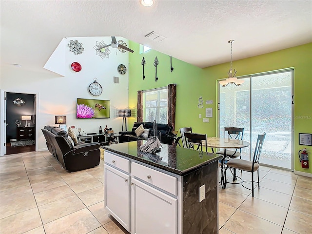 kitchen with a textured ceiling, light tile patterned flooring, white cabinets, open floor plan, and a wealth of natural light