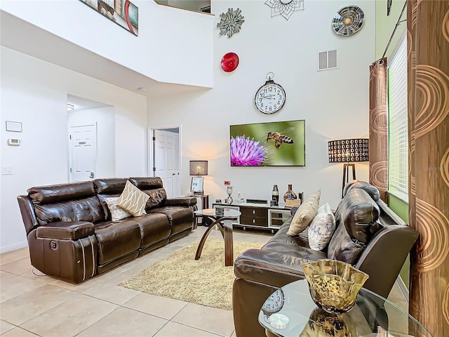 living room featuring light tile patterned floors, a high ceiling, and visible vents