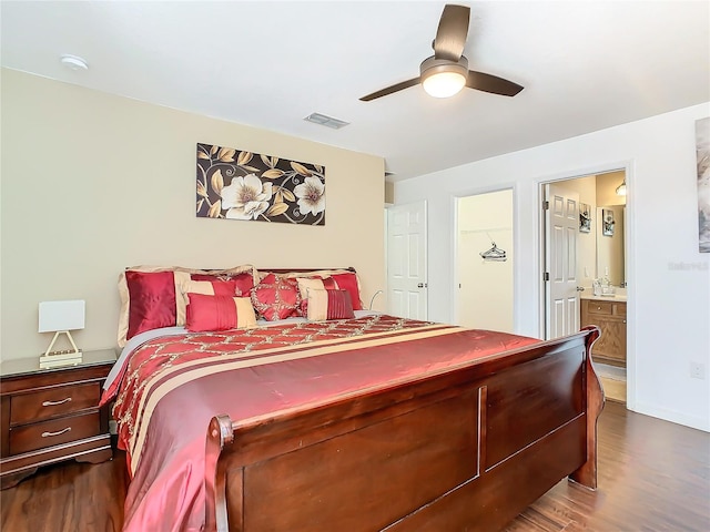 bedroom with dark wood-style floors, ceiling fan, visible vents, and ensuite bathroom