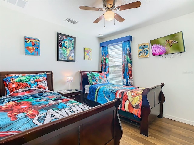 bedroom featuring baseboards, light wood-style flooring, visible vents, and a ceiling fan