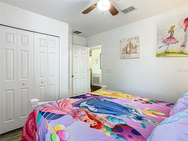 bedroom with dark wood-style floors, visible vents, and a closet