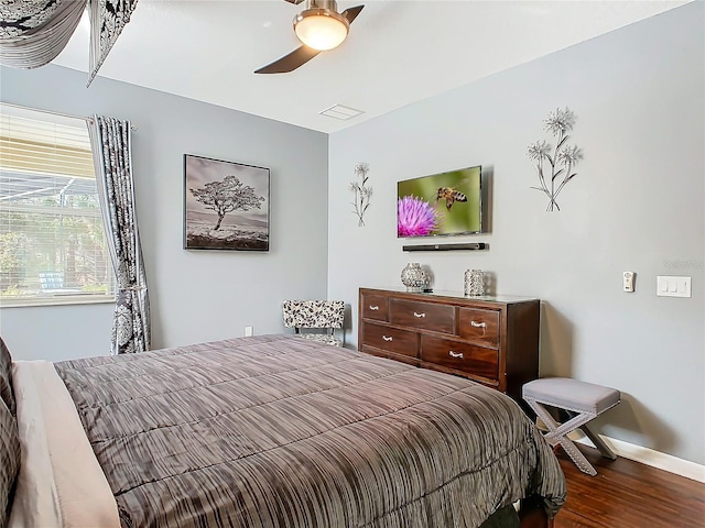 bedroom with ceiling fan, dark wood finished floors, visible vents, and baseboards