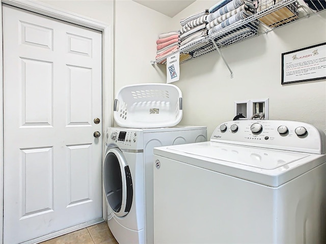 laundry area with laundry area, light tile patterned flooring, and washing machine and clothes dryer