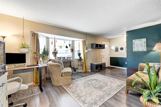 living area with a textured ceiling, baseboards, and wood finished floors