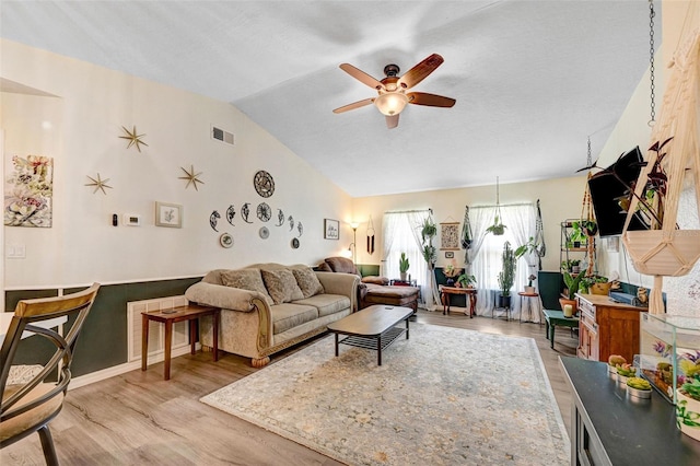 living room with lofted ceiling, ceiling fan, light wood finished floors, and visible vents