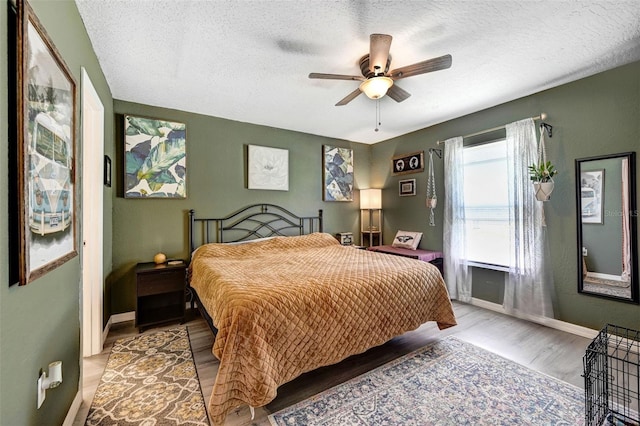 bedroom featuring light wood-style floors, a ceiling fan, baseboards, and a textured ceiling