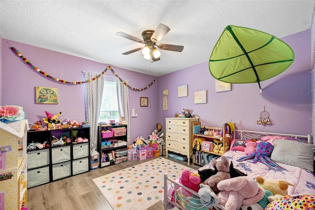 bedroom with a textured ceiling, a ceiling fan, and wood finished floors