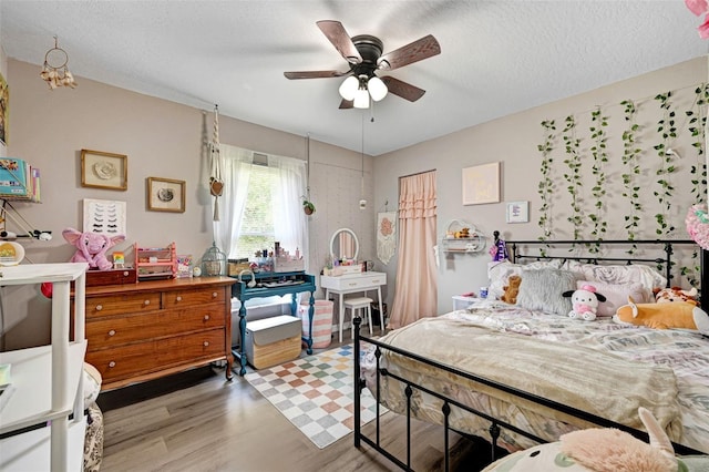 bedroom with a ceiling fan, a textured ceiling, and light wood finished floors