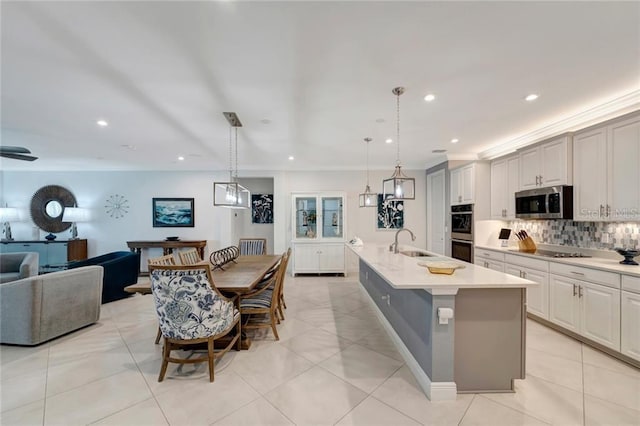 kitchen with decorative backsplash, open floor plan, light countertops, stainless steel appliances, and a sink