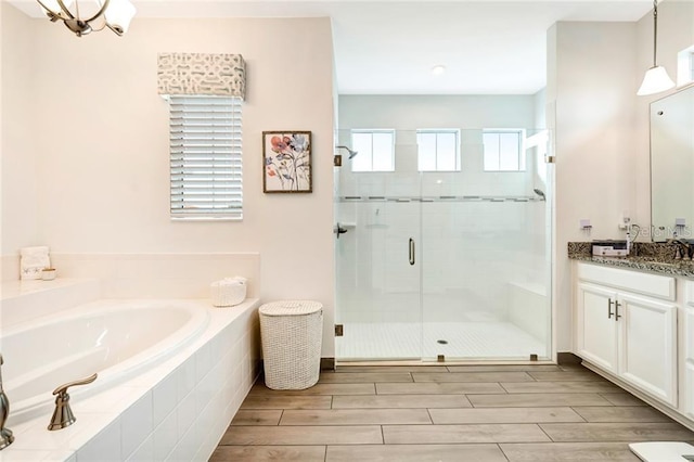 full bathroom featuring vanity, a shower stall, a bath, and wood tiled floor