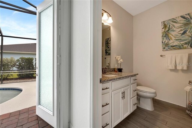 bathroom with baseboards, vanity, toilet, and wood finished floors