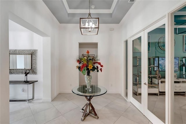 interior space with a tray ceiling, french doors, ornamental molding, a chandelier, and baseboards