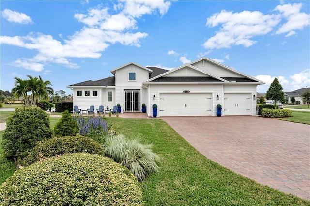 view of front of property featuring a front yard, decorative driveway, and an attached garage