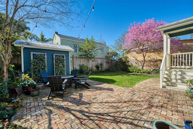 view of patio featuring outdoor dining area, a fenced backyard, and an outdoor structure